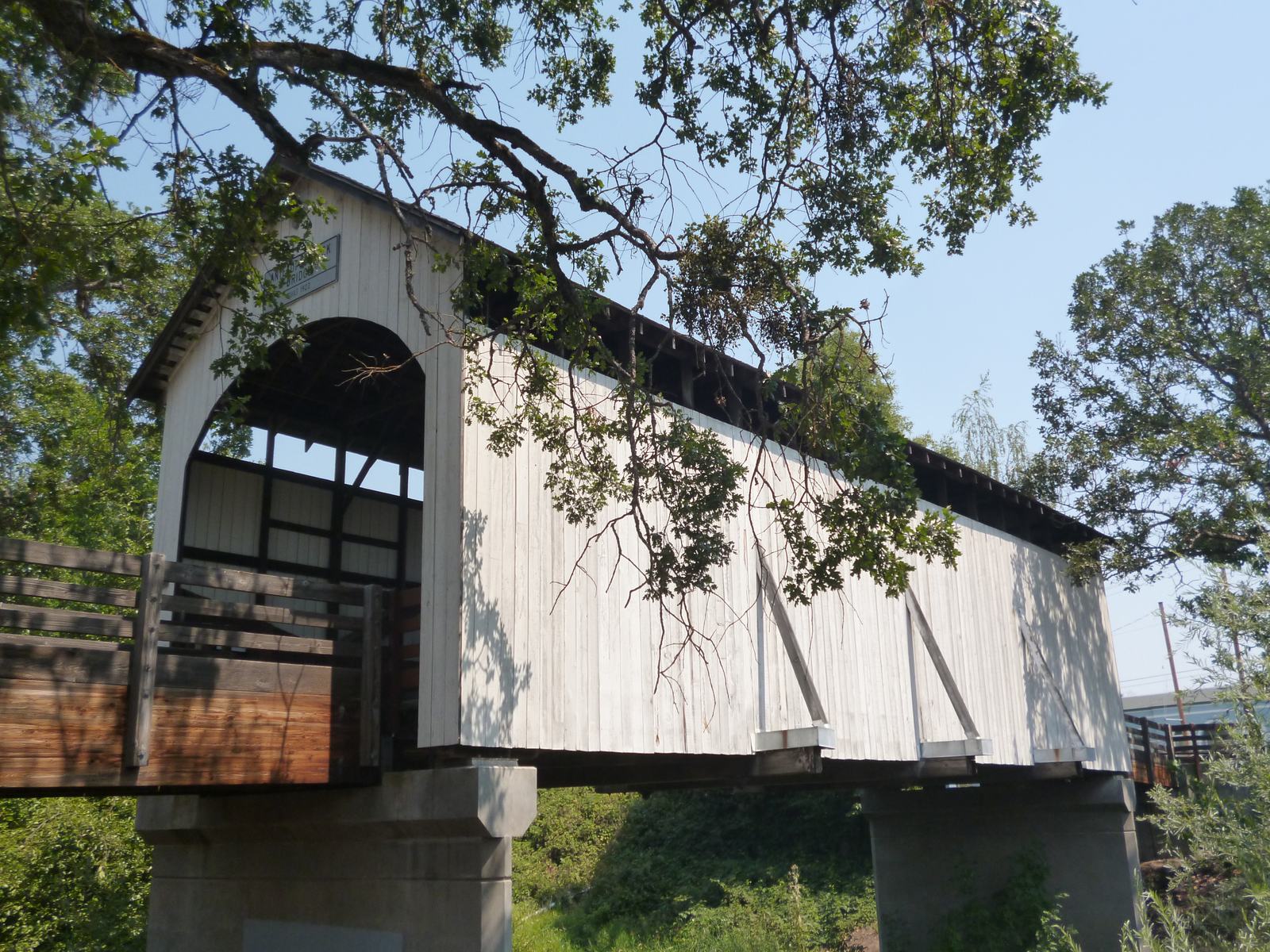The white Antelope Creek Covered Bridge in Eagle Point’s city park, framed by trees