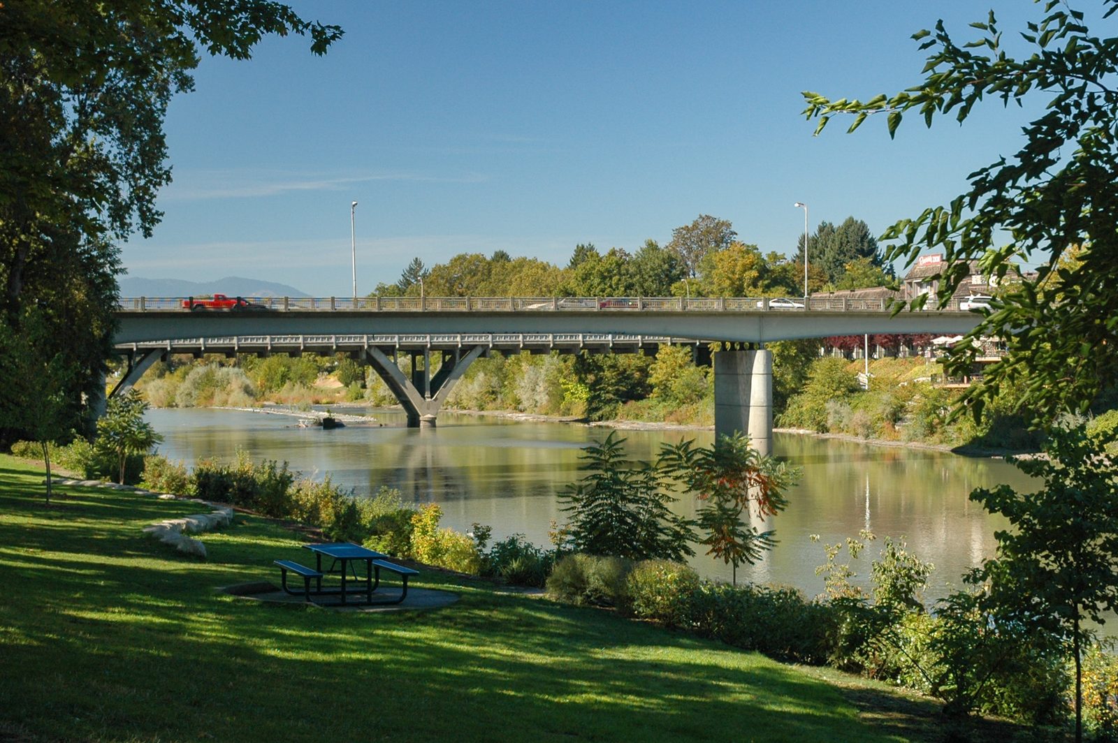 Riverside Park in Grants Pass, with green lawn, trees, and a bridge over the Rogue River